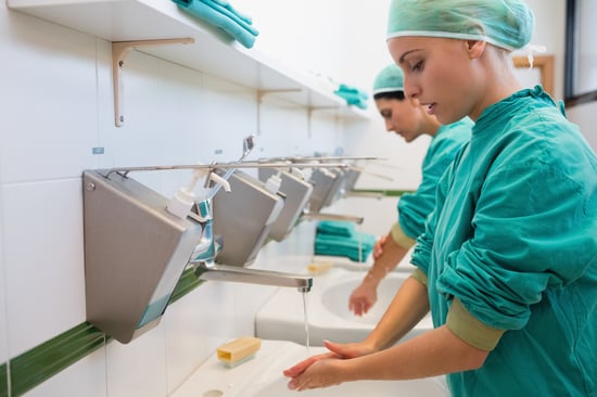 Two nurses scrubbing their hands in hospital sink