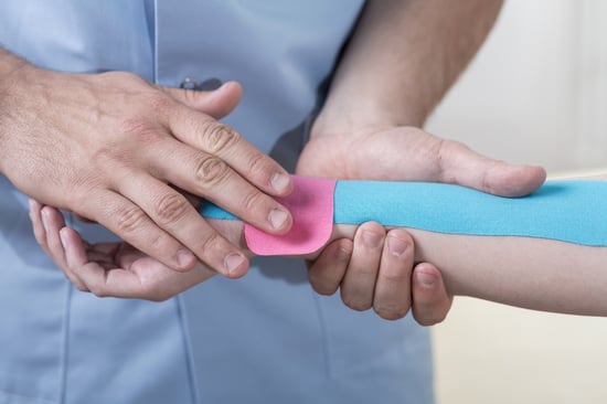 Young physiotherapist is taping arm and wrist