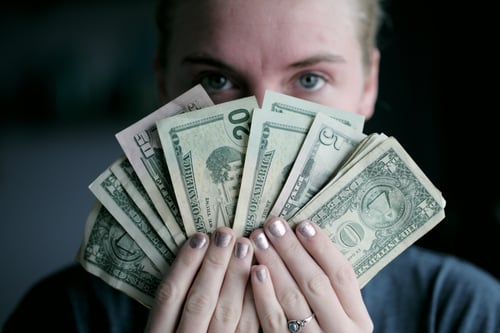 Woman holding money. Photo by Sharon McCutcheon on Unsplash